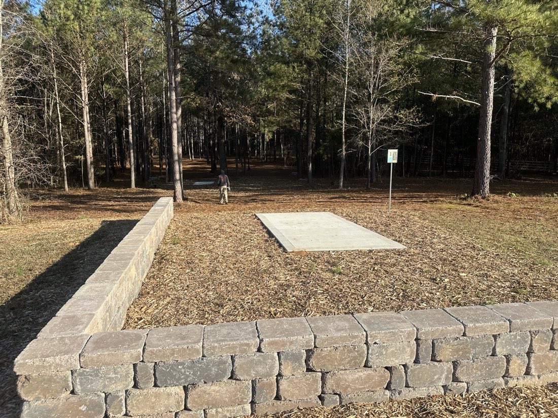 Stone-walled concrete tee pad in the woods