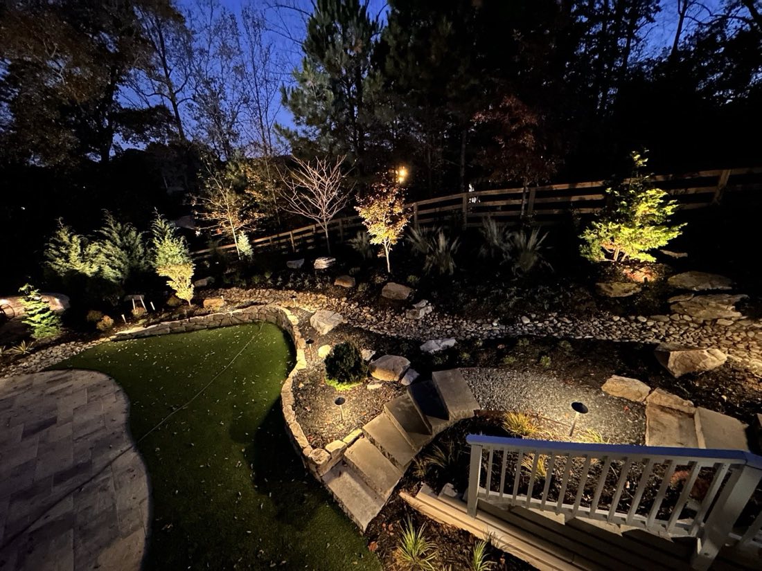 Accent-lit plantings and dry creek after dark