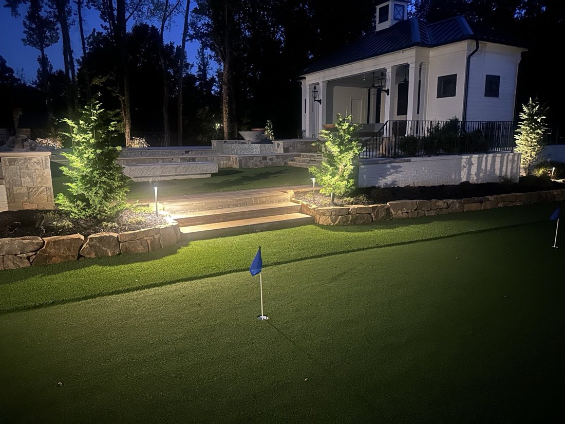 Putting green and pool house lit for the evening