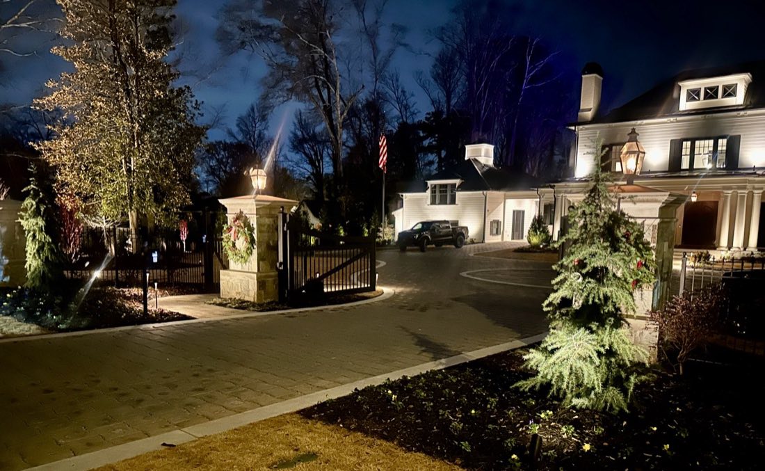 Estate entrance with lit gate piers and drive
