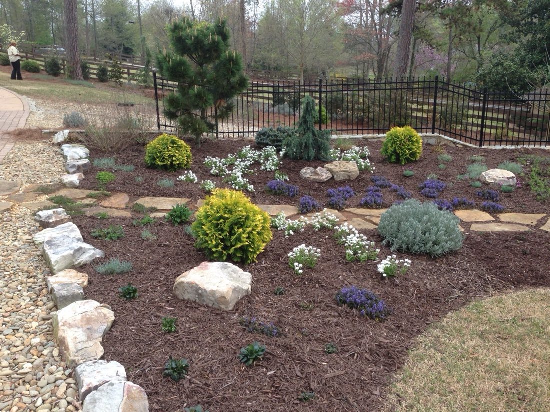 Rock-garden bed of dwarf conifers, boulders, and perennials