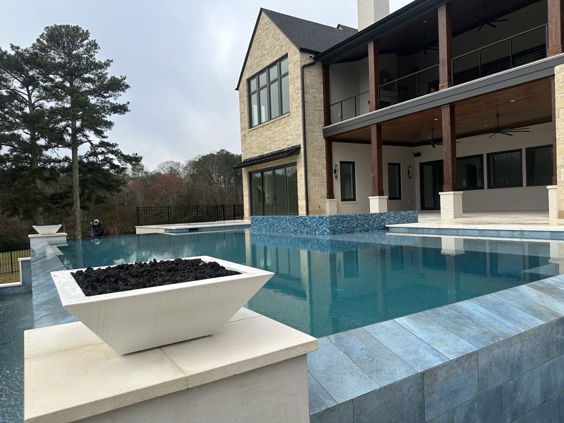 Infinity-edge pool with fire bowl and covered living space