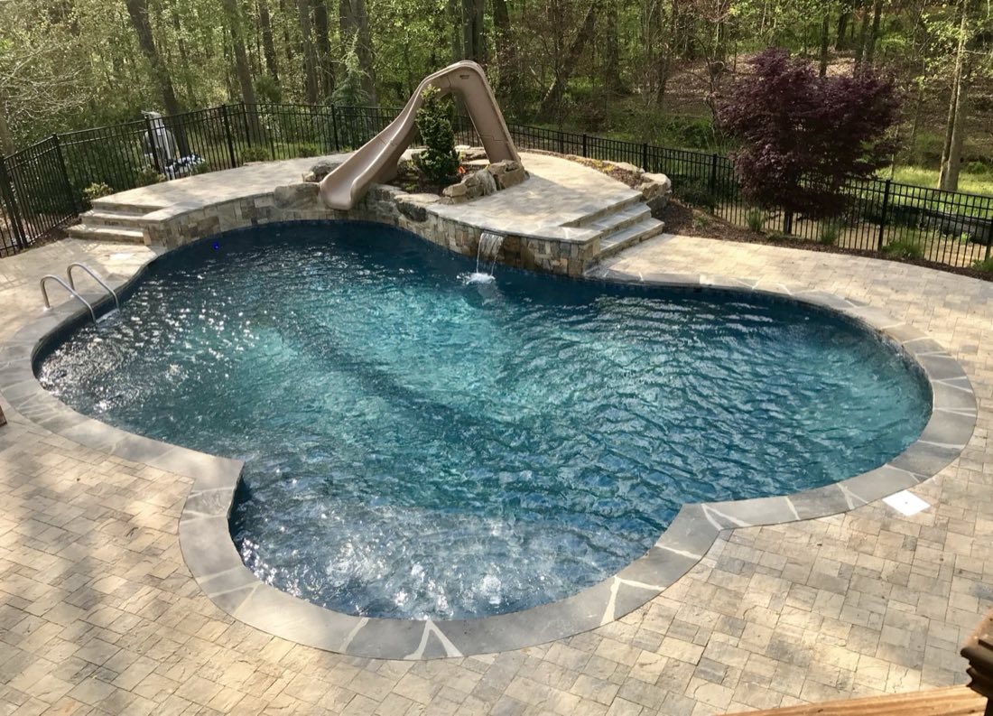 Freeform pool with stone waterfall and built-in slide