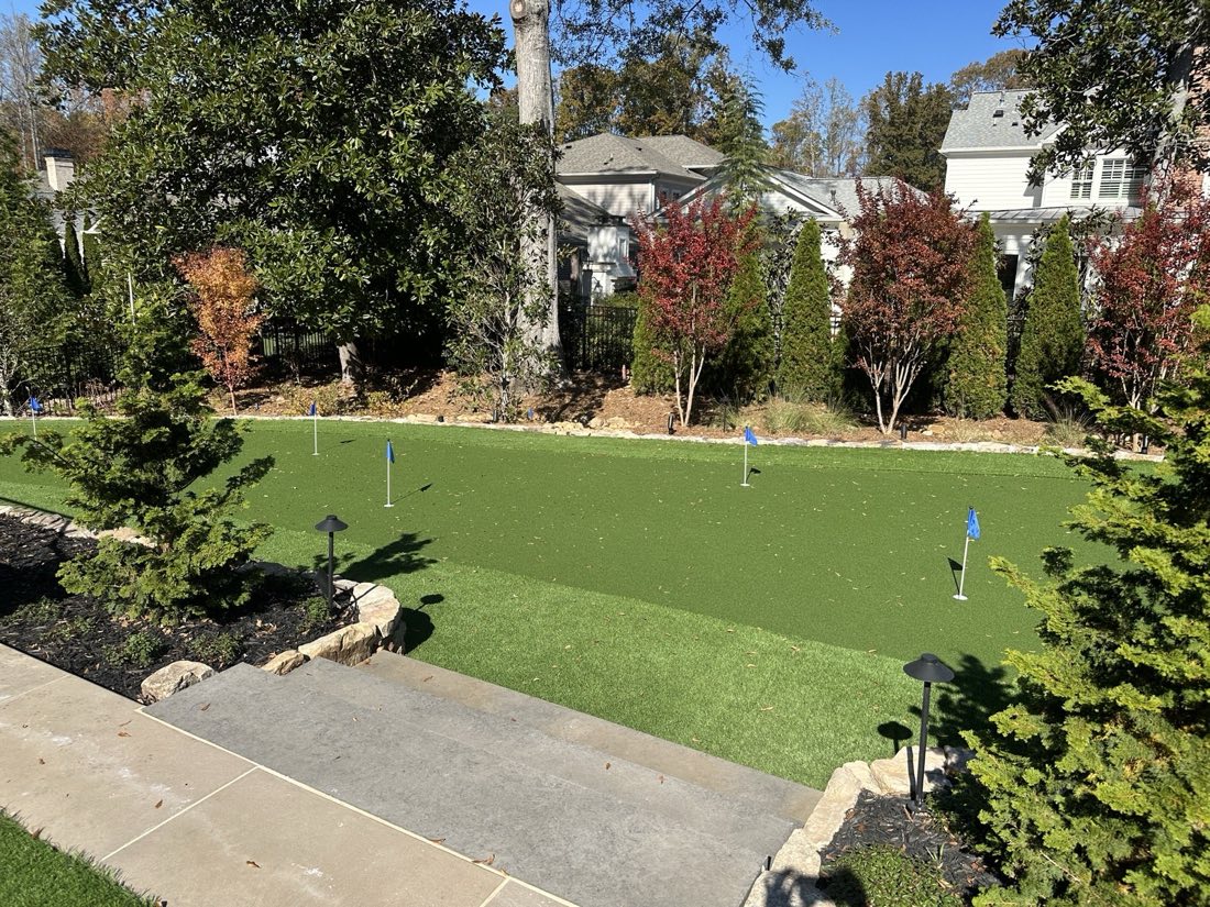 Putting green with multiple cups beside the drive