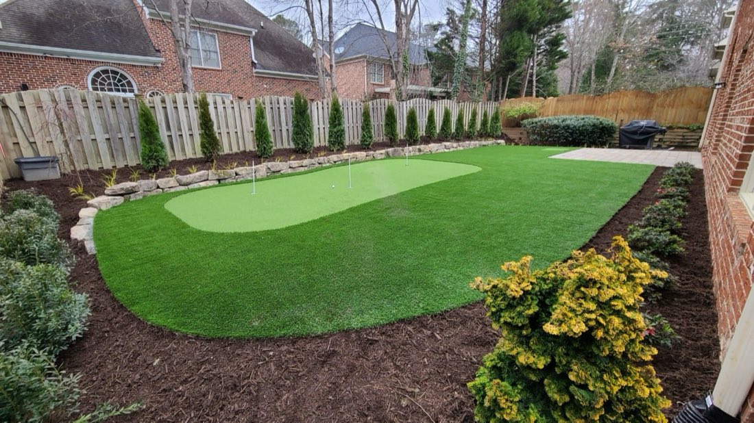Backyard green edged in mulch beds and privacy planting