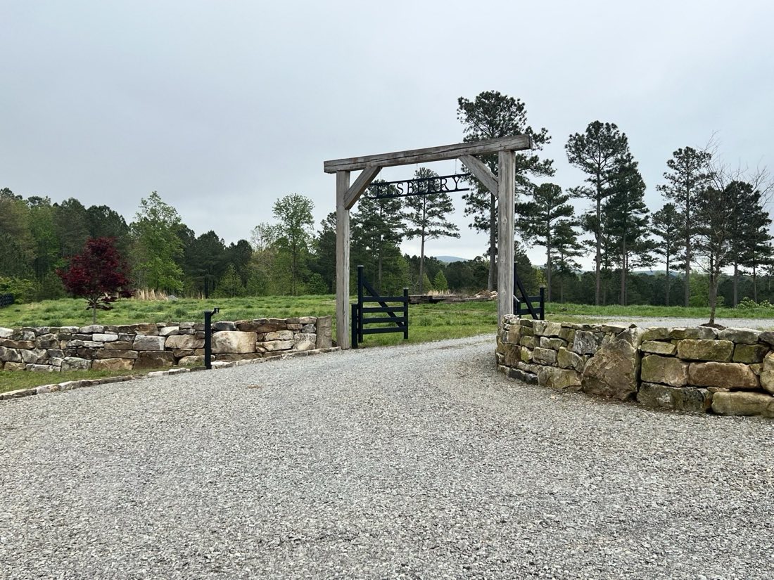 Boulder walls framing a farm entrance and timber gate